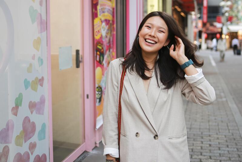 Young woman smiles while walking at a sidewalk